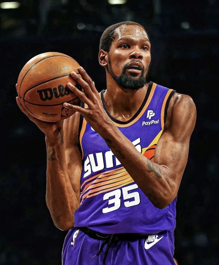 a man holding a basketball in his right hand and wearing a purple uniform with the number 35 on it