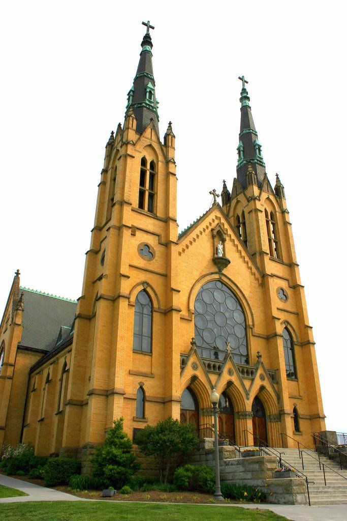 an old church with two steeples on it's sides and green grass in front