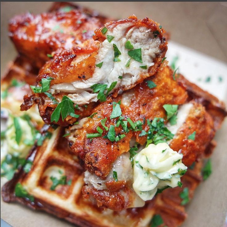 some chicken and waffles on a plate with parsley sprinkled around them