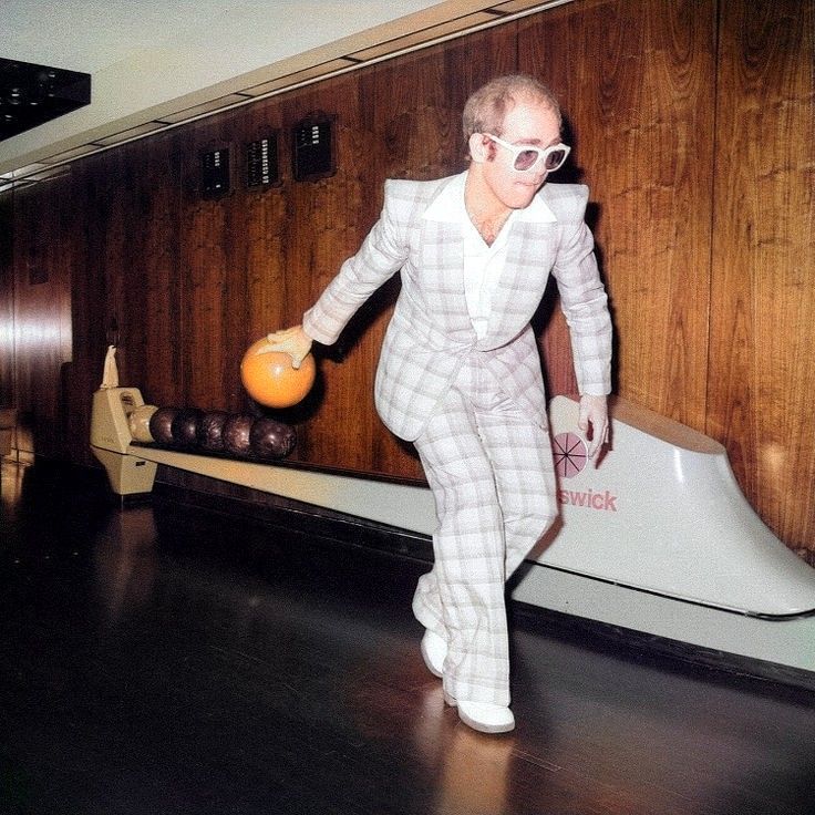 a man in white suit and sunglasses playing bowling