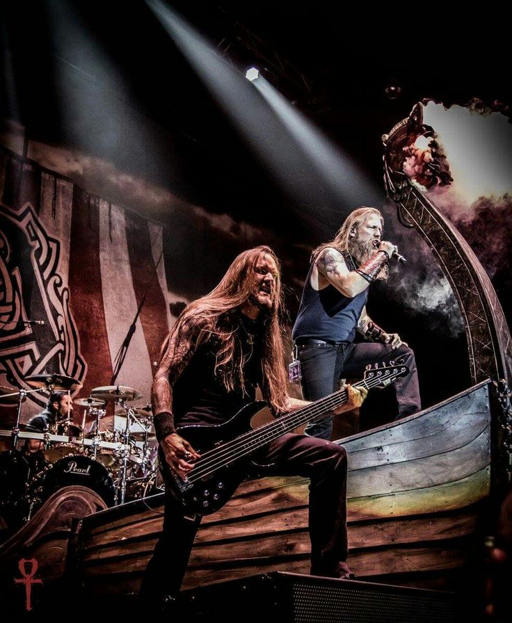 two men on stage with guitars and basses in front of an image of a pirate ship