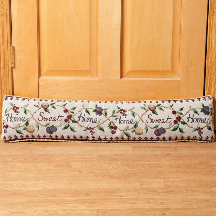 a decorative pillow on the floor in front of a door that says home sweet home