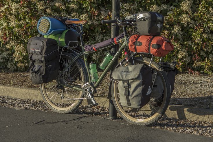 a bicycle parked next to a street light with backpacks on it's back