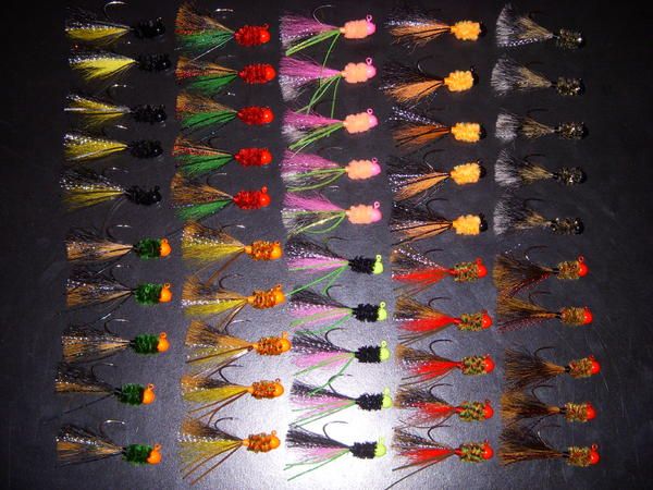 many different colored flies are arranged in rows on a black surface with white and orange trimmings