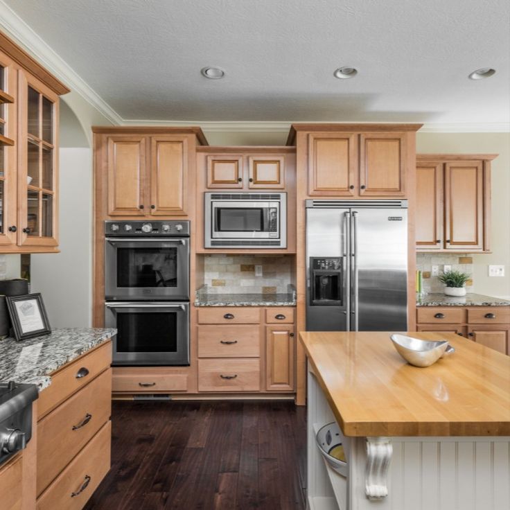 a large kitchen with wooden cabinets and stainless steel appliances, along with hardwood flooring