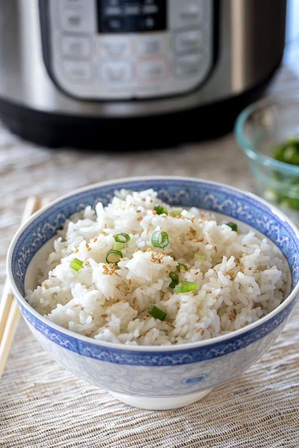 rice in a bowl with chopsticks next to an instant pressure cooker behind it