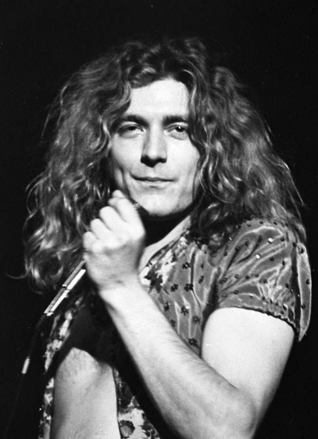 a man with long hair standing in front of a microphone