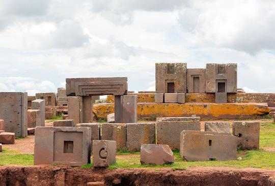 some concrete blocks sitting on top of a grass covered field next to rocks and dirt