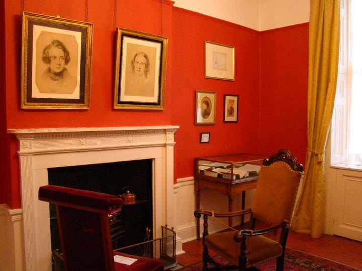 a living room with red walls and pictures on the wall, including an old fashioned chair