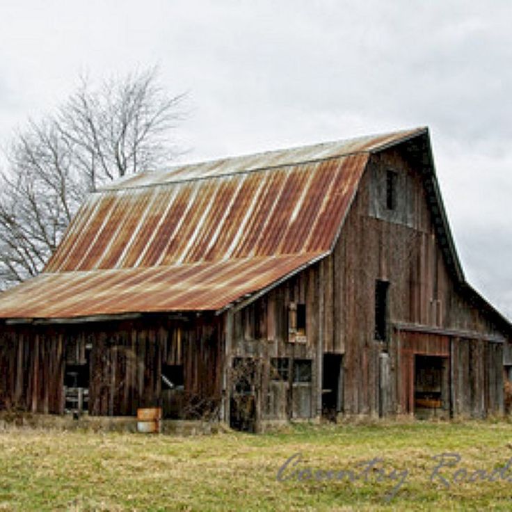 an old barn in the middle of a field with no grass or flowers on it