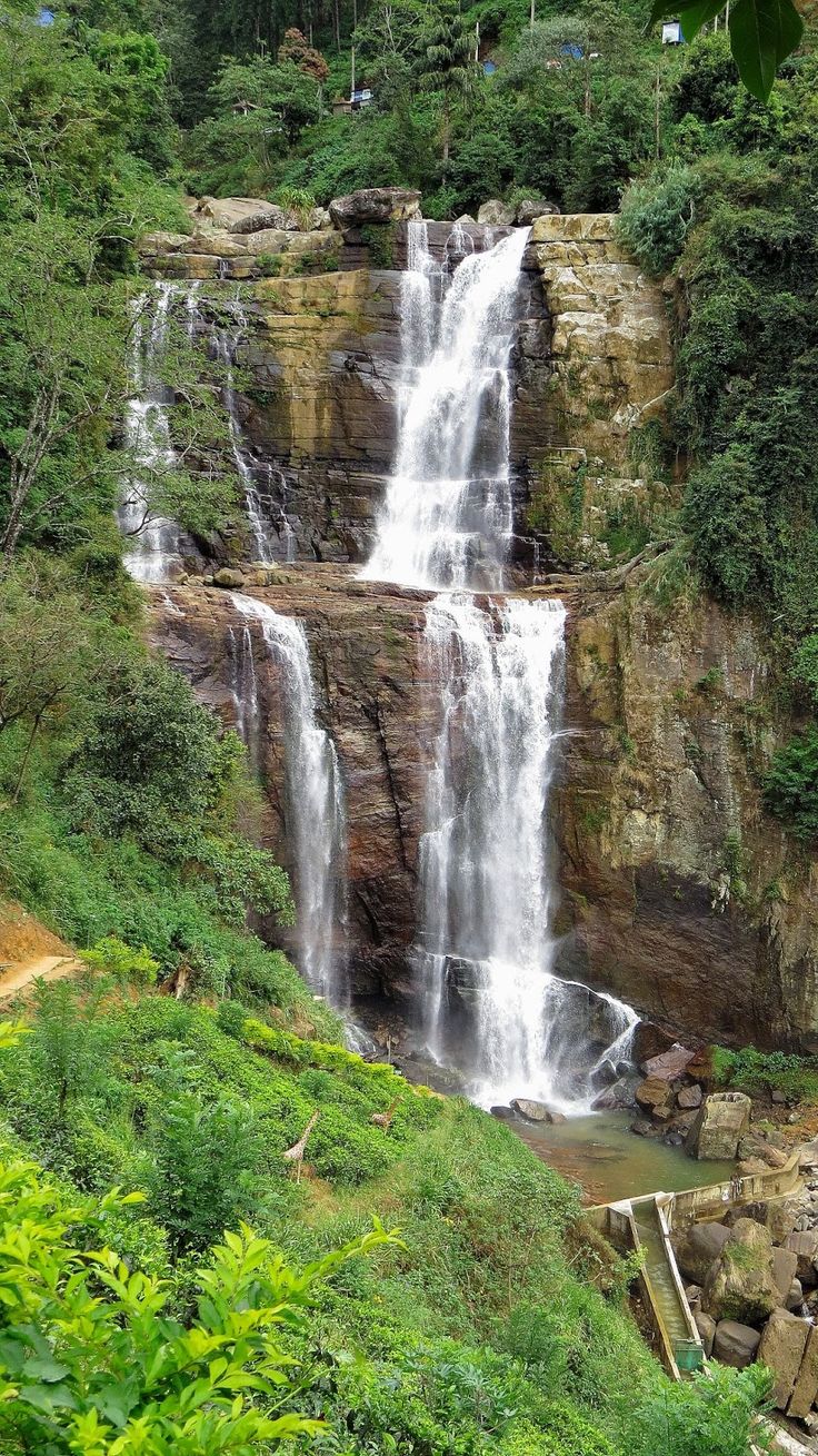 a large waterfall in the middle of a lush green forest