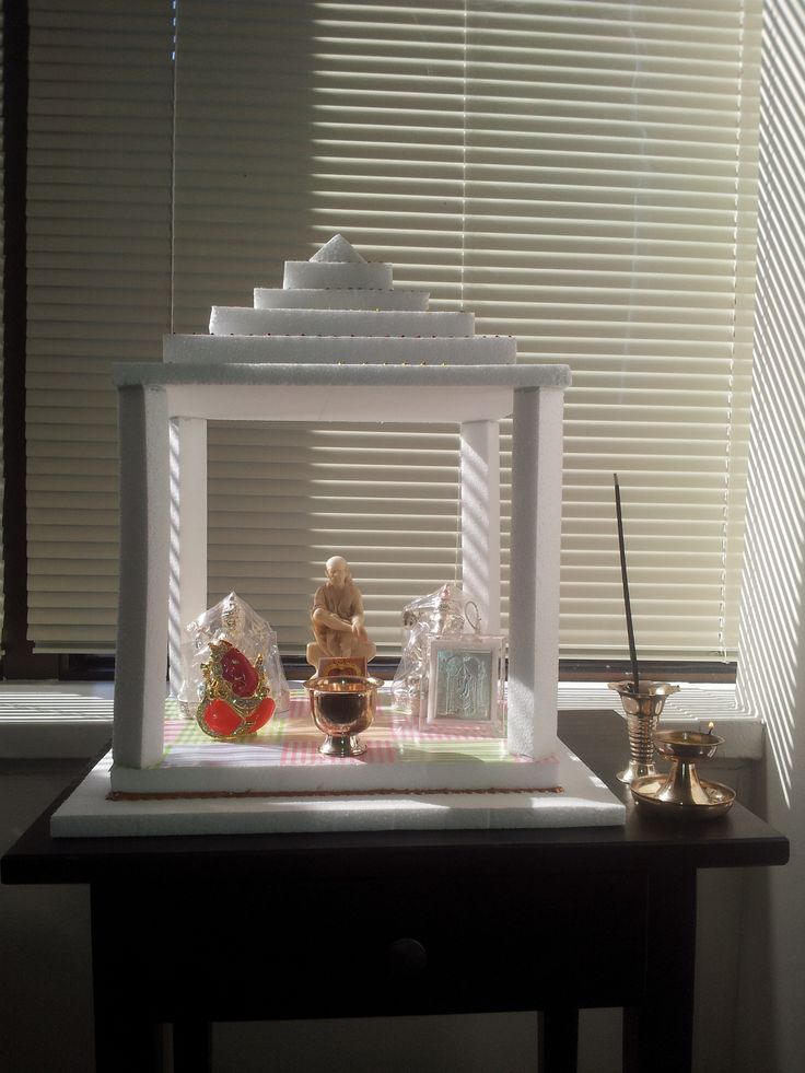 a small white box sitting on top of a table next to a window with blinds