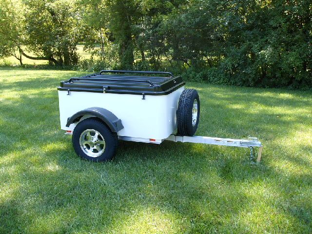 a white trailer sitting on top of a lush green field