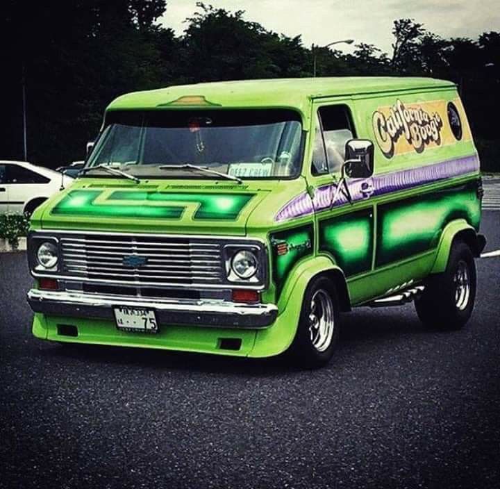 an old green van is parked in a parking lot