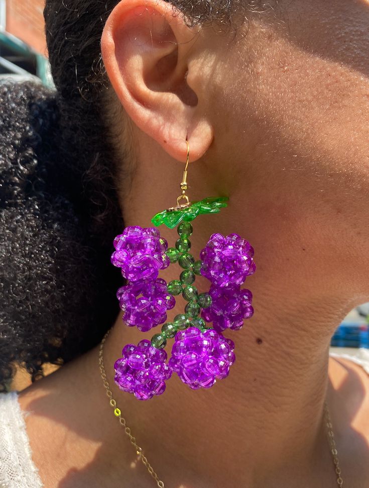 a close up of a person wearing purple flowers on their earrings and necklace