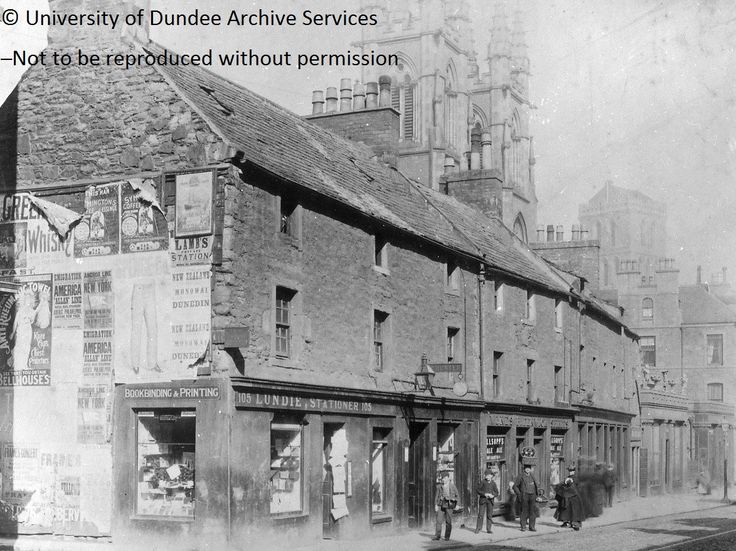 an old black and white photo of people standing in front of a building on the street