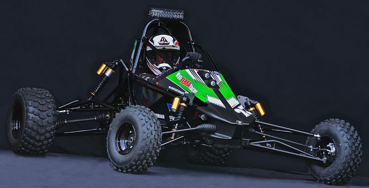 a green and black dune buggy on a dark background