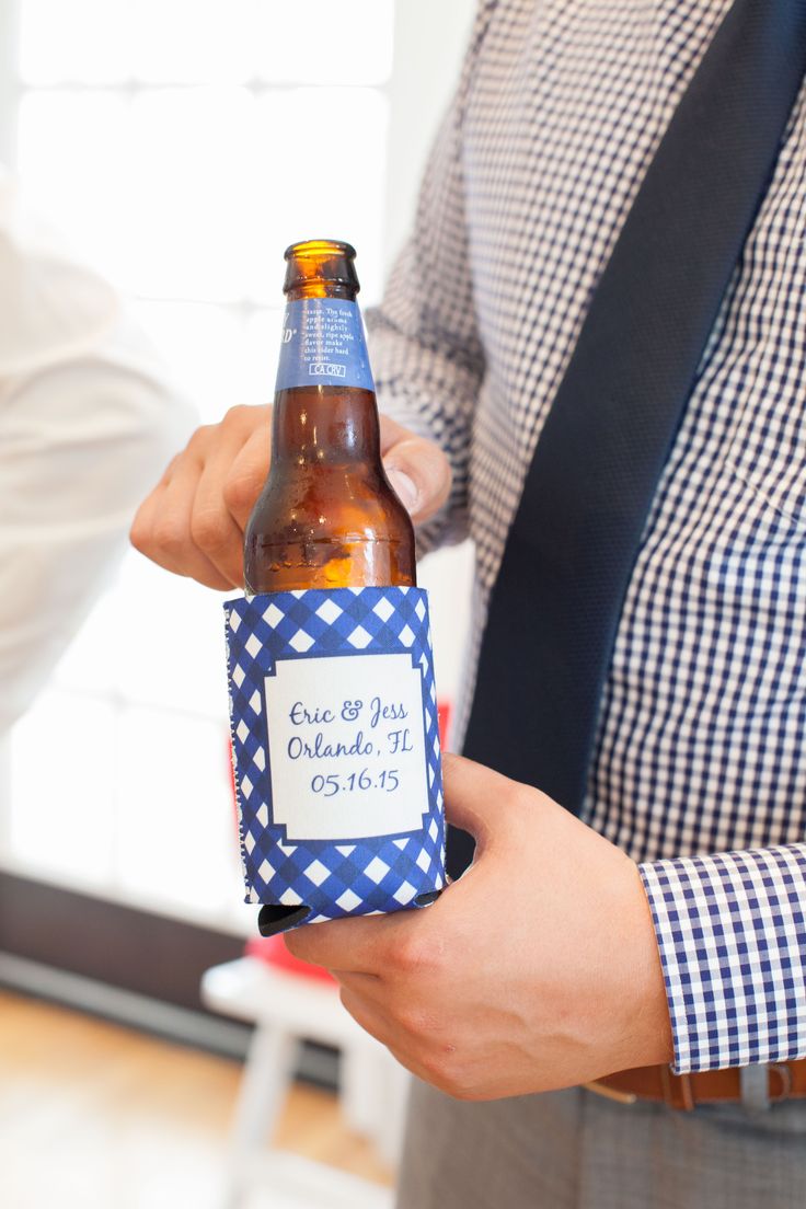 a man holding a beer bottle in his hand with a blue and white checkered label on it