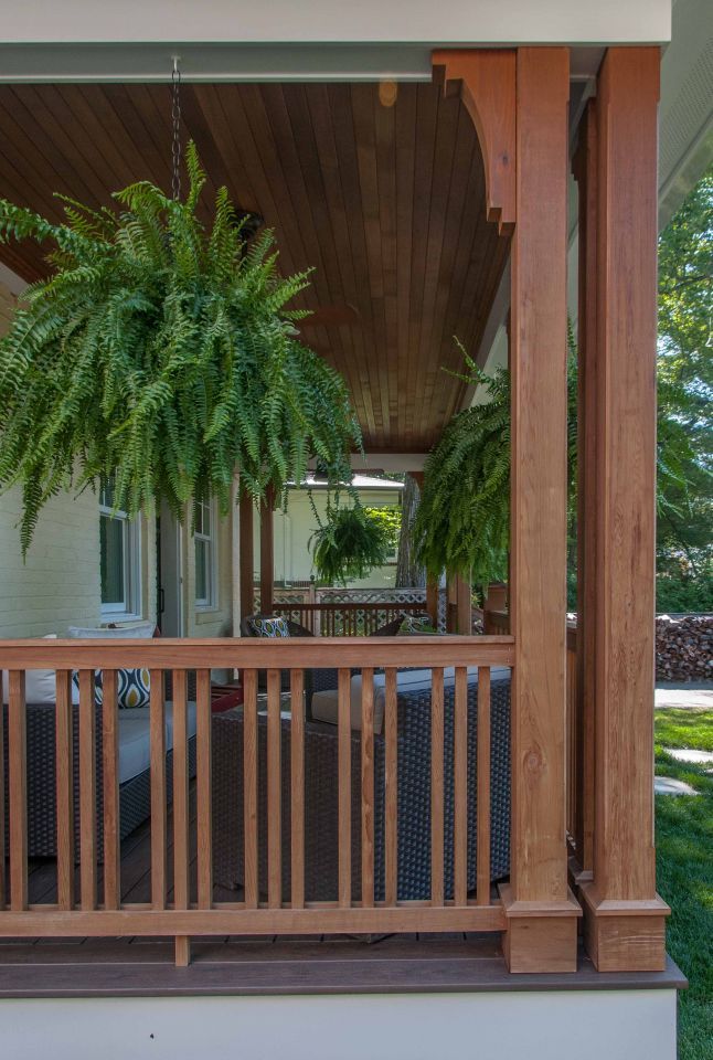 a porch with wooden railings and potted plants