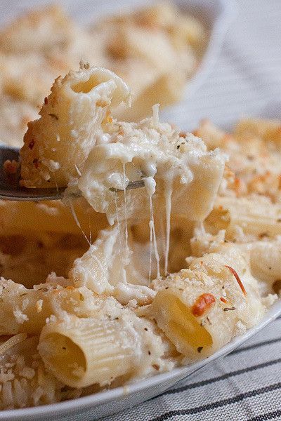 a fork full of macaroni and cheese being lifted from the casserole dish