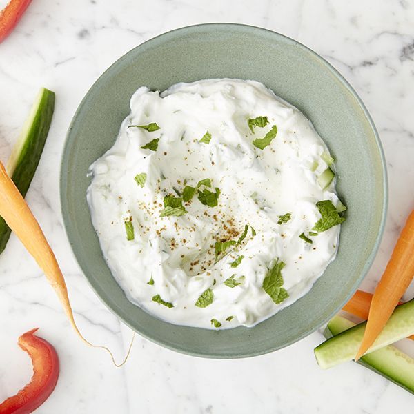 a bowl filled with sour cream surrounded by carrots, celery and peppers