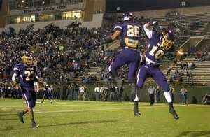 two football players jumping up in the air to catch a ball while others watch from the bleachers