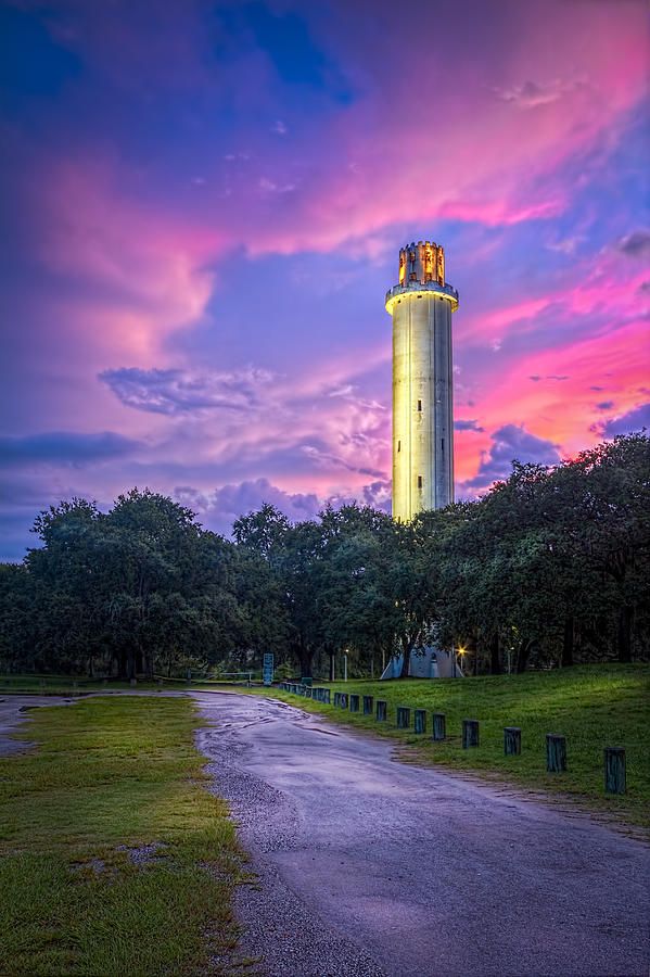 a tall white tower sitting on top of a lush green field under a purple sky