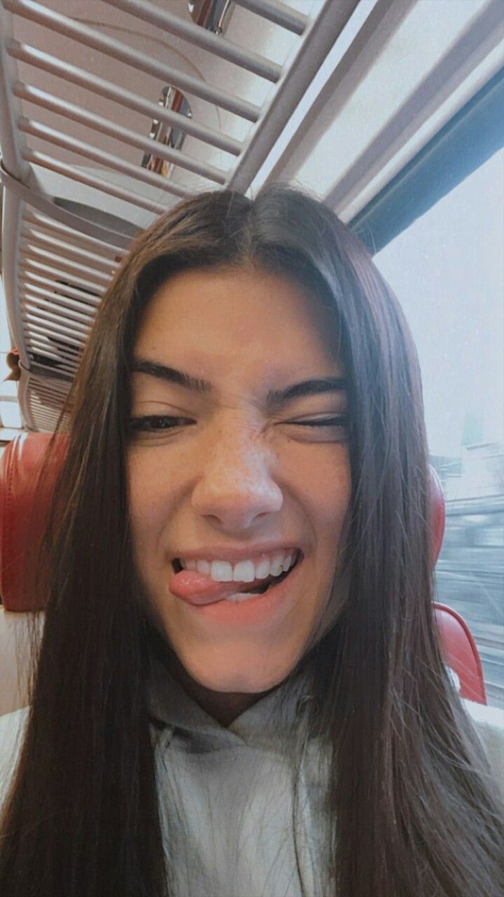 a woman with long brown hair is smiling and looking at the camera while on a bus