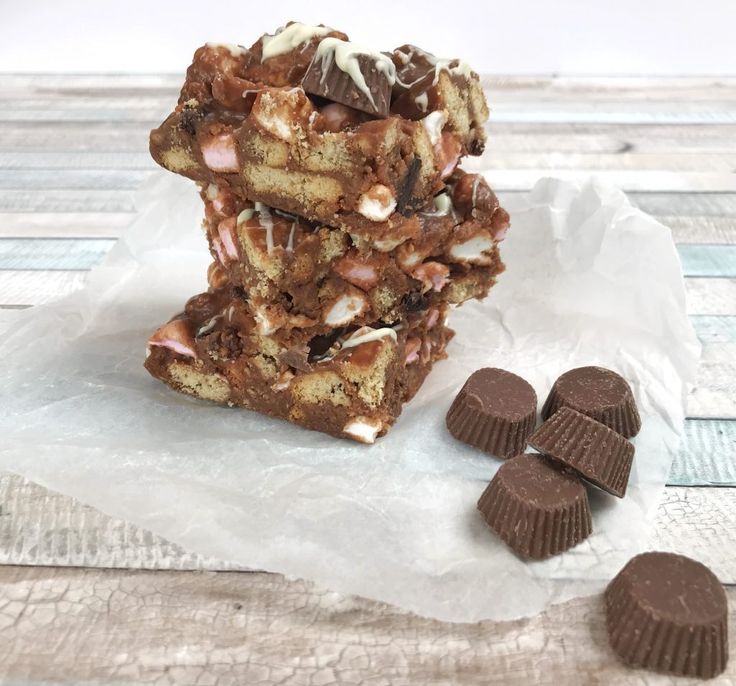 a stack of chocolate candy bars sitting on top of parchment paper next to some cookies