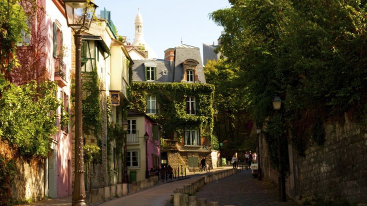 an alley way with buildings and trees on both sides, in the middle of town