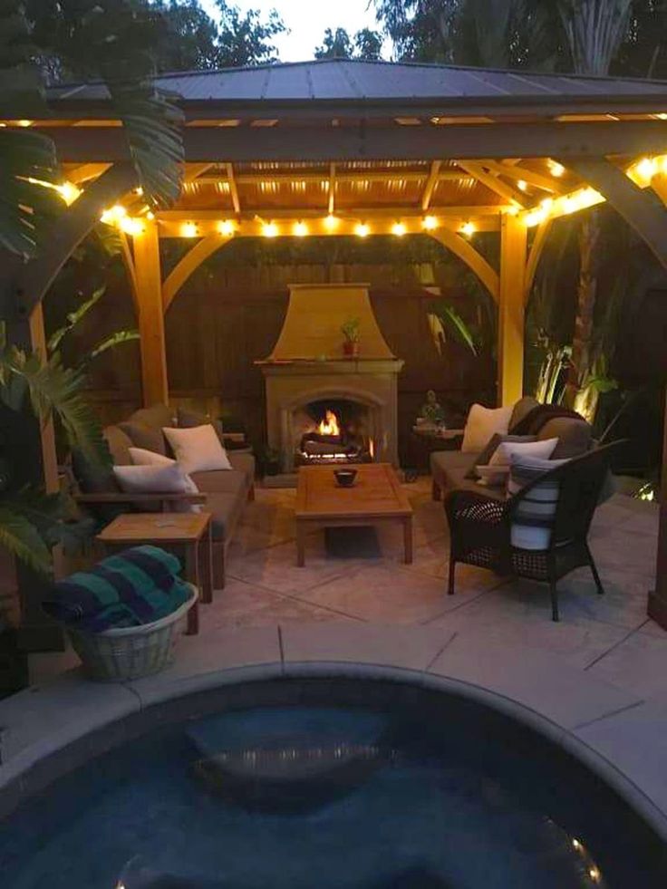 an outdoor living area with a fire place and patio furniture in the evening time,