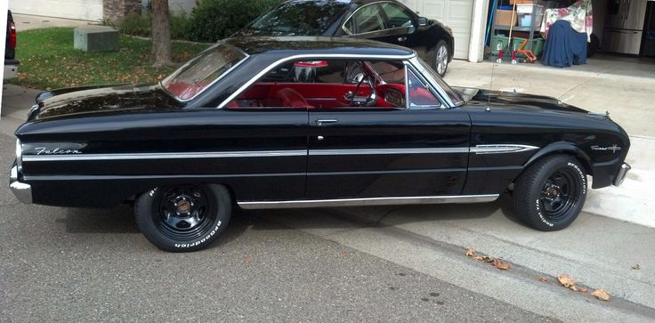 an old black car is parked on the street