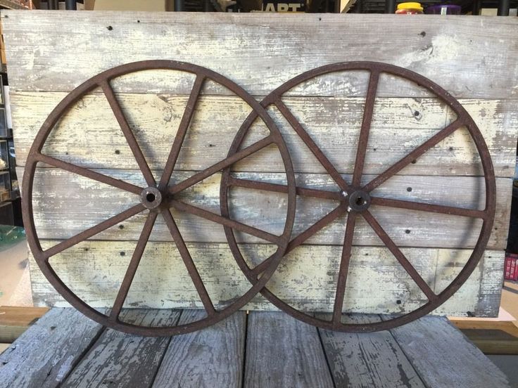 two old wooden wagon wheels are sitting on a table in front of a wood pallet