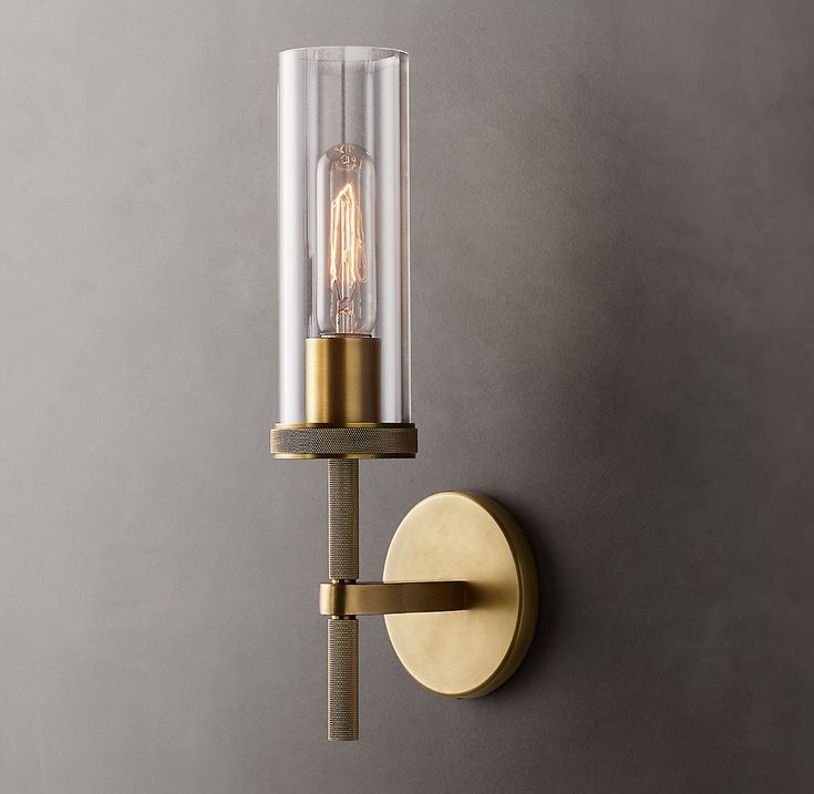 a light that is on the wall next to a gray wall with a glass tube