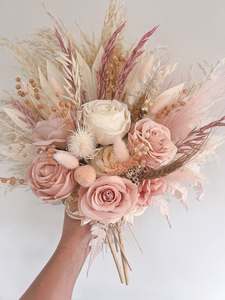 a hand holding a bouquet of flowers and feathers