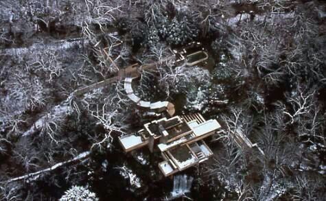 an aerial view of a house surrounded by trees in the woods with snow on the ground