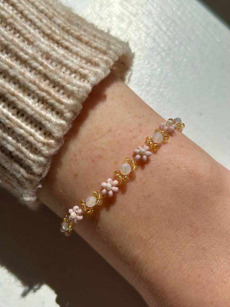 Meet the "Rosemarie" bracelet, a delicate flower beaded bracelet made with baby pink, golden, and cream pearlescent seed beads. Its dainty, feminine design and neutral palette make it a versatile accessory that effortlessly complements any outfit. Whether you're dressing up for a special occasion or adding a subtle elegance to your everyday attire, the "Rosemarie" bead bracelet is your perfect companion. Embrace its timeless charm and understated beauty - explore the 'Rosemarie' flower beaded br Adjustable Rose Gold Flower Beaded Bracelets, Delicate Adjustable Pink Bracelet, Pink Delicate Adjustable Bracelet, Adjustable Delicate Beaded Bracelets With Flower Charm, Dainty Beaded Bracelet With Flower Charm, Delicate White Bracelets For Spring, Handmade Delicate Rose Gold Beaded Bracelets, Adjustable Handmade Rose Gold Pearl Bracelet, White Delicate Bracelet For Spring