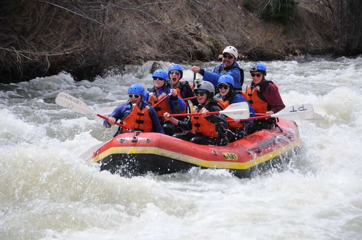 a group of people riding on the back of a raft down a river in white water