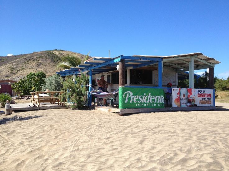 a food stand on the beach with people sitting at it