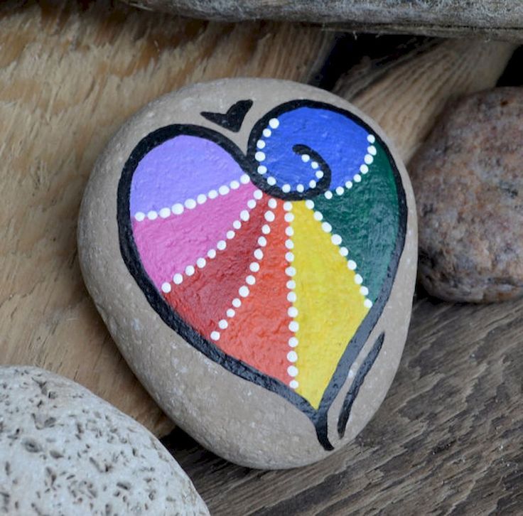 two rocks with designs painted on them sitting next to each other in front of some rocks