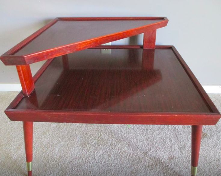 a wooden table with two trays on each side and one sitting on the floor