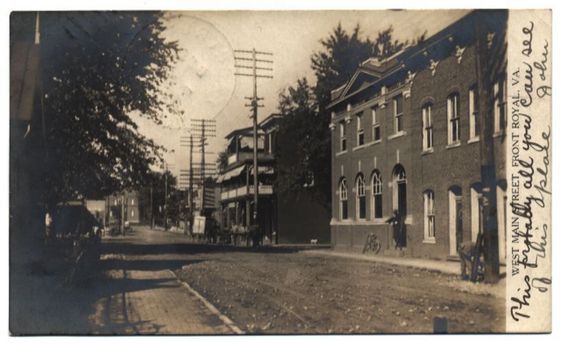 an old black and white photo of a street with buildings on both sides, trees in the background