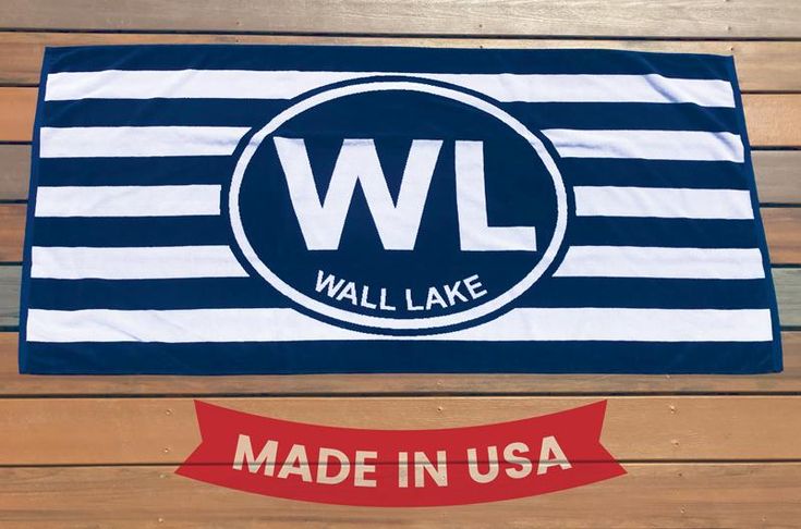 wall lake made in usa beach towel on wooden deck with red and white ribbon around it