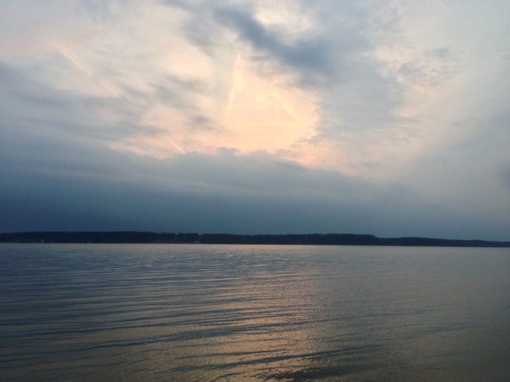 the sky is very cloudy over the water and there are clouds in the distance above it