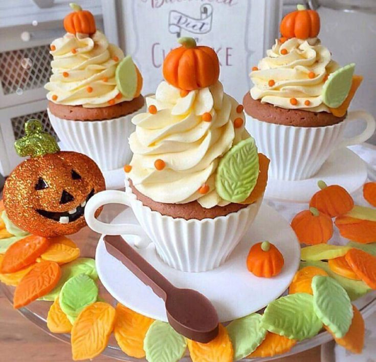 cupcakes with frosting and pumpkin decorations are on a plate next to a sign