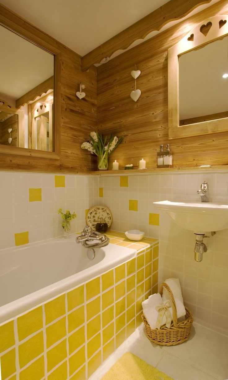 a bathroom with yellow and white tiles on the walls, sink, mirror and bathtub