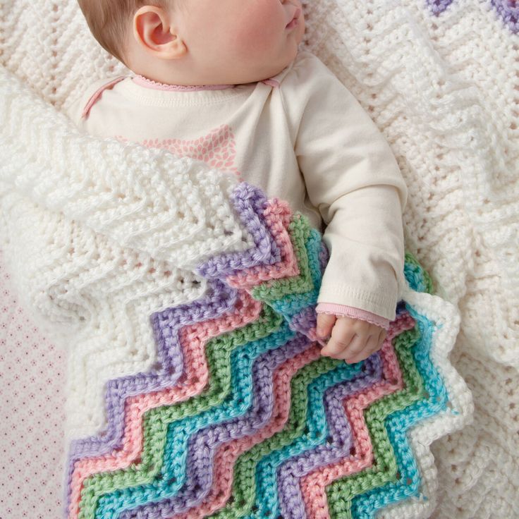 a baby laying on top of a colorful blanket