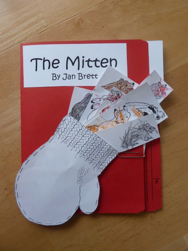 the mitten is cut out from paper and placed on top of a red book