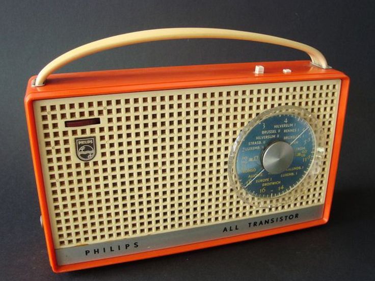 an orange radio sitting on top of a black table next to a white and blue clock