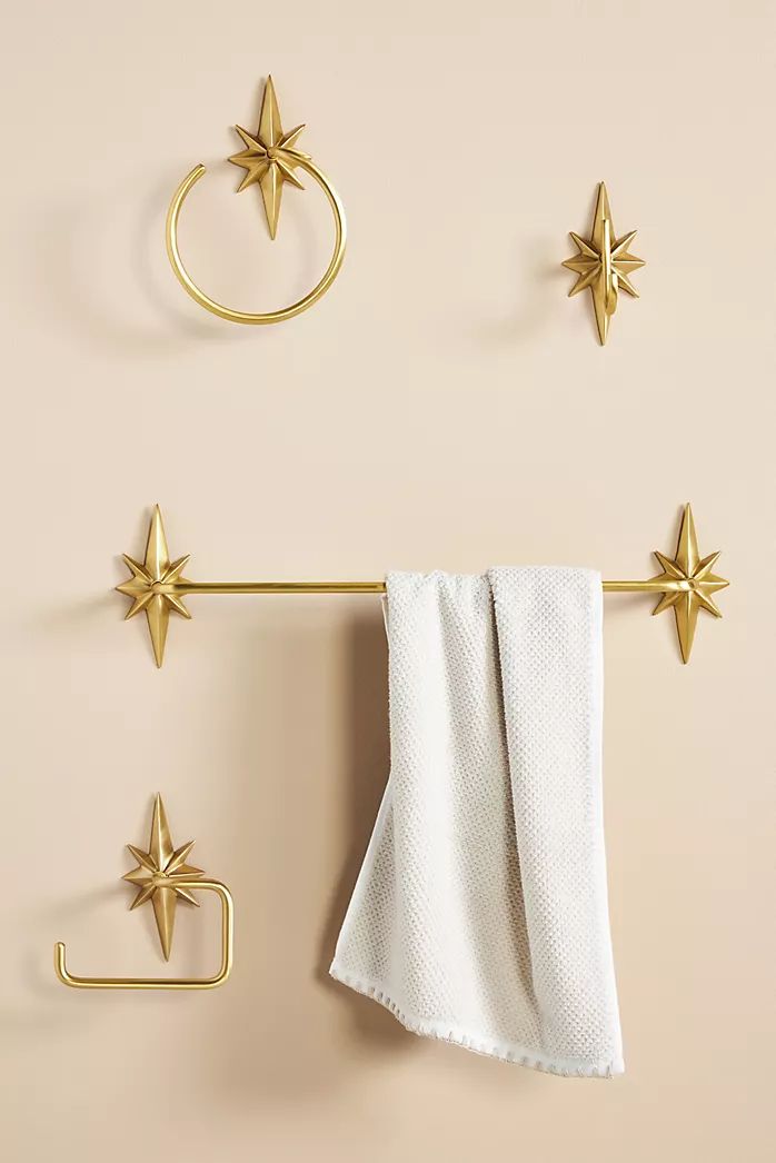 three gold stars hang on the wall next to two towels and a towel rack with hooks